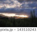 雲の間から光が差し込む幻想的な風景、草むらと山々のシルエット 143510243
