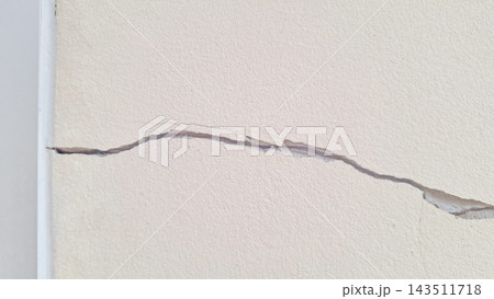 A long horizontal crack runs across the textured white plaster wall surface 143511718