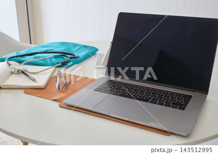Doctor workspace with laptop, stethoscope, and scrubs Doctor workspace with laptop, stethoscope, and scrubs 143512995