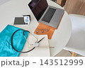 Telehealth doctor workspace with laptop and medical equipment 143512999