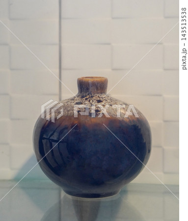 front view antique brown and black small round ceramic vase, on a glass shelf, white ceramic wall background, object, decor, fashion, copy space front view antique brown and black small round ceramic vase, on a glass shelf, white ceramic wall background, object, decor, fashion, copy space 143513538