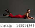 Woman in a red dress lies with her feet raised in black heels 143514865