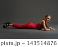 Woman in a red dress lies prone on a gray studio floor 143514876