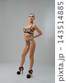 Woman in geometric mesh lingerie and heels standing in studio 143514885
