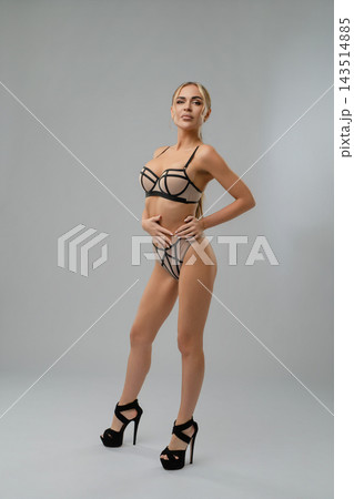 Woman in geometric mesh lingerie and heels standing in studio Woman in geometric mesh lingerie and heels standing in studio 143514885