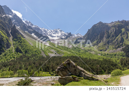 Scenic valley landscape with snow peaks and forest near Mount Ullu Tau 143515724
