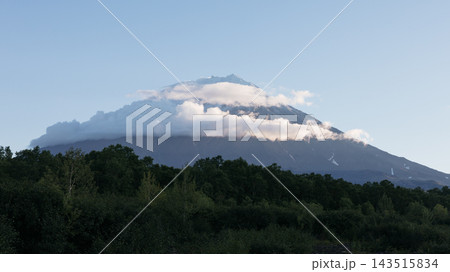 Majestic volcanic peak covered in soft white clouds above dense green forest Majestic volcanic peak covered in soft white clouds above dense green forest 143515834