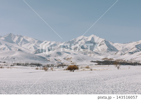 Snow covered mountain ridges and rural winter valley in Kyrgyzstan Snow covered mountain ridges and rural winter valley in Kyrgyzstan 143516057