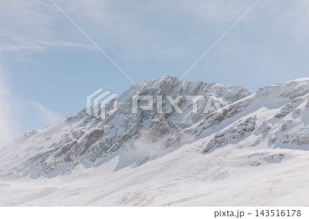 Snow covered peak in Alay Valley against pale blue sky in winter Snow covered peak in Alay Valley against pale blue sky in winter 143516178