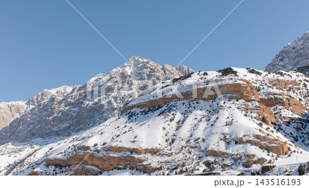 Snow covered rocky mountain peaks against clear blue sky in winter Snow covered rocky mountain peaks against clear blue sky in winter 143516193