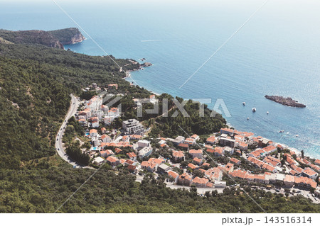 Aerial high view of coastal town Sveti Stefan with red tiled roofs and blue sea Aerial high view of coastal town Sveti Stefan with red tiled roofs and blue sea 143516314