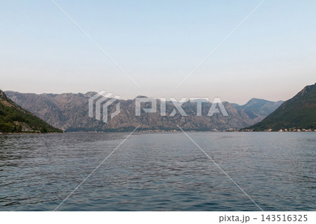 Scenic view across the calm waters of the Bay of Kotor with rocky mountains Scenic view across the calm waters of the Bay of Kotor with rocky mountains 143516325