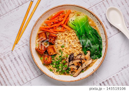 Noodles ramen miso soup served with tofu, bok choy, carrots, and mushrooms. 143519106