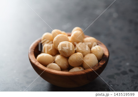 Macadamia nuts in olive wood bowl on terrazzo surface Macadamia nuts in olive wood bowl on terrazzo surface 143519599