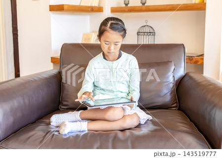 真剣な表情でタブレットを操作する小学生の女の子 真剣な表情でタブレットを操作する小学生の女の子 143519777