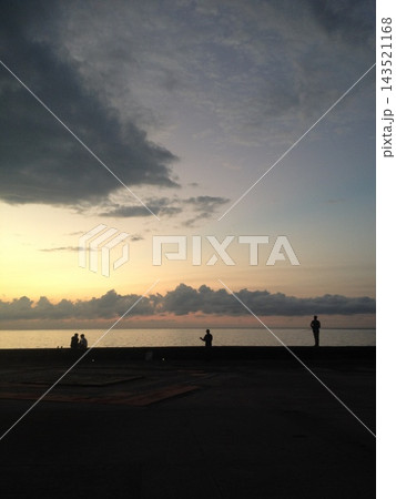 夕暮れの海辺で過ごす人々のシルエットと空 143521168