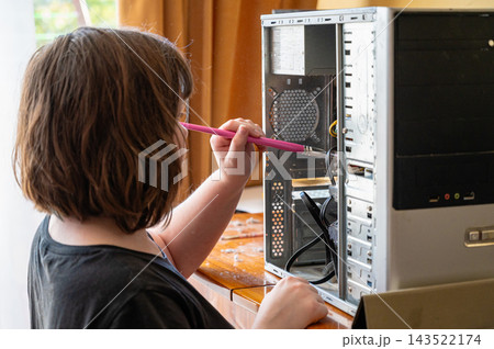 Teenage girl using tool while fixing open desktop computer at home 143522174