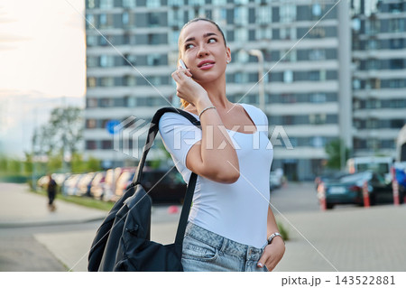 Young woman talking on smartphone outdoors against city building background Young woman talking on smartphone outdoors against city building background 143522881
