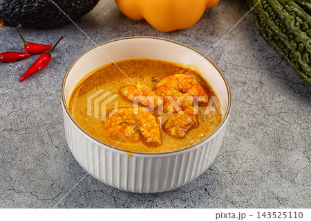 Grey textured surface bowl filled with rich spicy shrimp curry in thick yellow gravy Grey textured surface bowl filled with rich spicy shrimp curry in thick yellow gravy 143525110