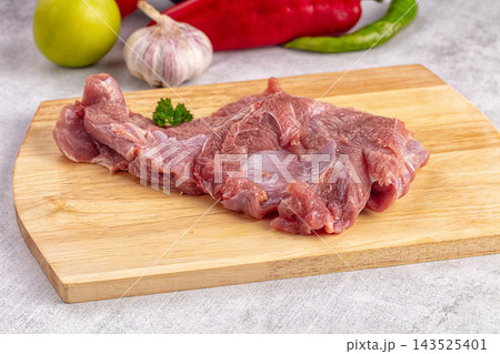 Wooden cutting board with raw turkey fillet garnished by parsley sprig and surrounded by garlic bulb, green apple, red and green peppers, food preparation Wooden cutting board with raw turkey fillet garnished by parsley sprig and surrounded by garlic bulb, green apple, red and green peppers, food preparation 143525401