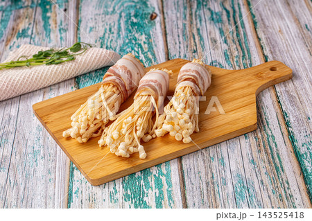 Wooden cutting board with bacon wrapped enoki mushrooms, Asian appetizer snack 143525418
