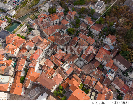 Kotor Montenegro old town fills aerial view, with dense stone buildings and terracotta roofs. Historic streets cluster beside wooded hillside and narrow waterway, revealing compact Adriatic 143525682