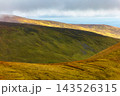 Green, moss-covered hills under a cloudy, shifting Irish sky. 143526315