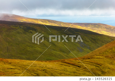 Green, moss-covered hills under a cloudy, shifting Irish sky. Green, moss-covered hills under a cloudy, shifting Irish sky. 143526315
