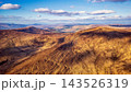 Rugged mountainous landscape featuring rolling hills and vast golden plains under a bright sunny sky during late afternoon. 143526319