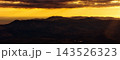 Golden clouds glow brightly above the dark ridges of the Irish mountains as the day ends and evening light covers the landscape. 143526323