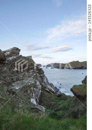 Rugged coastal landscape overlooking the Atlantic Ocean near Baltimore in West Cork Ireland during a calm afternoon with rocky cliffs and green hills. 143526328