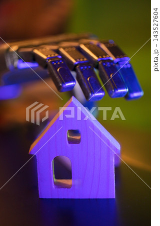 Colorful harmonica resting above a small wooden house model with vivid purple and blue lighting, closeup view of an abstract musical object and miniature shelter Colorful harmonica resting above a small wooden house model with vivid purple and blue lighting, closeup view of an abstract musical object and miniature shelter 143527604