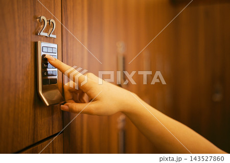 Hand pressing keypad on a secure locker with number 22 visible, wooden locker background, indicating a storage or security system in a modern facility Hand pressing keypad on a secure locker with number 22 visible, wooden locker background, indicating a storage or security system in a modern facility 143527860