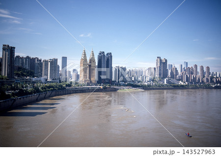 Urban skyline of Chongqing, China featuring modern skyscrapers along the Yangtze River with a clear blue sky and a small boat in the foreground Urban skyline of Chongqing, China featuring modern skyscrapers along the Yangtze River with a clear blue sky and a small boat in the foreground 143527963