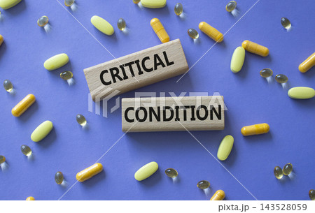 CRITICAL CONDITION symbol. Concept word CRITICAL CONDITION on wooden blocks. Beautiful purple background with pills. Medicine and CRITICAL CONDITION. Copy space 143528059