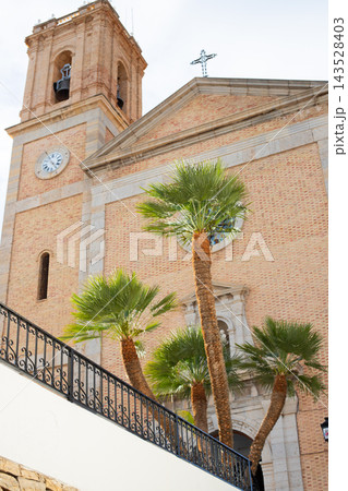 Historic Altea church bell tower and facade with lush palm trees under a bright sky, a beautiful Spanish travel destination for family holidays Historic Altea church bell tower and facade with lush palm trees under a bright sky, a beautiful Spanish travel destination for family holidays 143528403