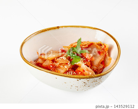 Spicy Korean kimchi with sesame seeds in a ceramic bowl, isolated on white background Spicy Korean kimchi with sesame seeds in a ceramic bowl, isolated on white background 143529112