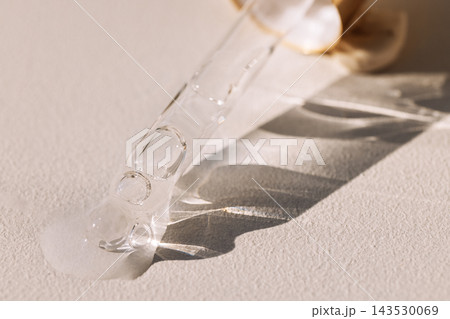 Close-up of a glass pipette with a drop of moisturizing serum with bubbles 143530069