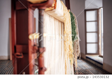 Traditional weaving loom with colorful threads in a bright room, showcasing intricate craftsmanship and textile artistry, perfect for cultural and artistic representation Traditional weaving loom with colorful threads in a bright room, showcasing intricate craftsmanship and textile artistry, perfect for cultural and artistic representation 143530132