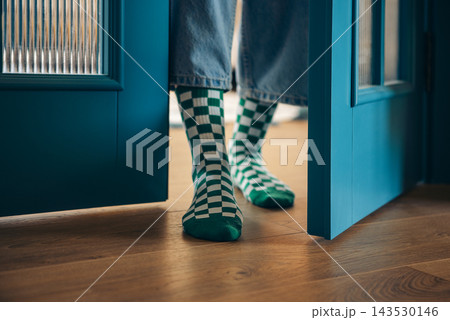 Close-up of a female legs in funny plaid socks near open blue doors Close-up of a female legs in funny plaid socks near open blue doors 143530146