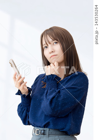 スマートフォンを持って考える女性 スマートフォンを持って考える女性 143530264