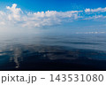 Wide blue sea beneath a dramatic cloud-filled sky, with reflections creating a peaceful scenic travel background. 143531080