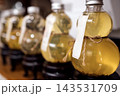 Decorative glass bottles filled with herbal infusion displayed on wooden stand, featuring labels and twine accents, arranged in a row for aesthetic presentation 143531709