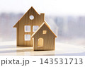 Wooden house models in light with cut-out windows and doors, showcasing a minimalist design on a bright surface against a blurred background 143531713