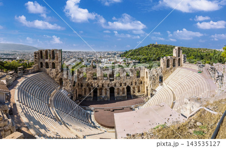 Odeon of Herodes Atticus ancient theater ruins with Athens cityscape in background under blue sky 143535127