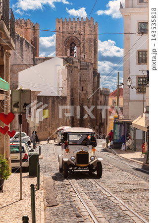 Vintage Tourist Car on Cobblestone Street Near Lisbon Cathedral, Portugal Vintage Tourist Car on Cobblestone Street Near Lisbon Cathedral, Portugal 143535818