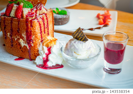 Honey toast with strawberries, mint leaves and red sauce, served beside whipped cream and vanilla ice cream topped with chocolate, with a glass of extra sauce on a white plate and lava cake nearby. Honey toast with strawberries, mint leaves and red sauce, served beside whipped cream and vanilla ice cream topped with chocolate, with a glass of extra sauce on a white plate and lava cake nearby. 143538354