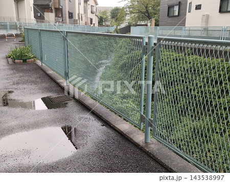 住宅地の川沿いのフェンスと水たまり 住宅地の川沿いのフェンスと水たまり 143538997
