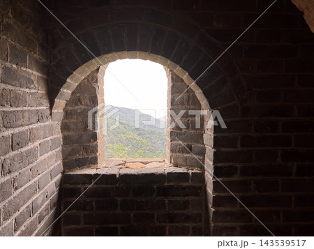 Ancient brick embrasure in the Great Wall of China overlooking a green mountain valley near Beijing  143539517