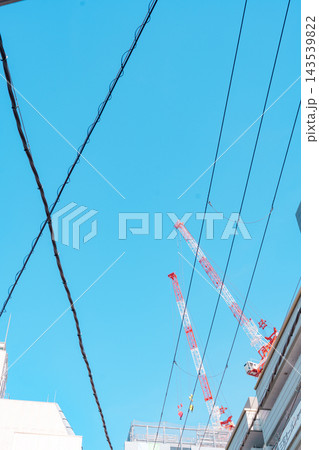 電線越しに見える工事現場のクレーン 電線越しに見える工事現場のクレーン 143539822